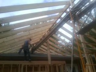 Rafters going up over a new addition with a worker on the wall in Portsmouth